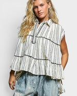 Woman wearing a striped shirt with ruffled layers on a plain background