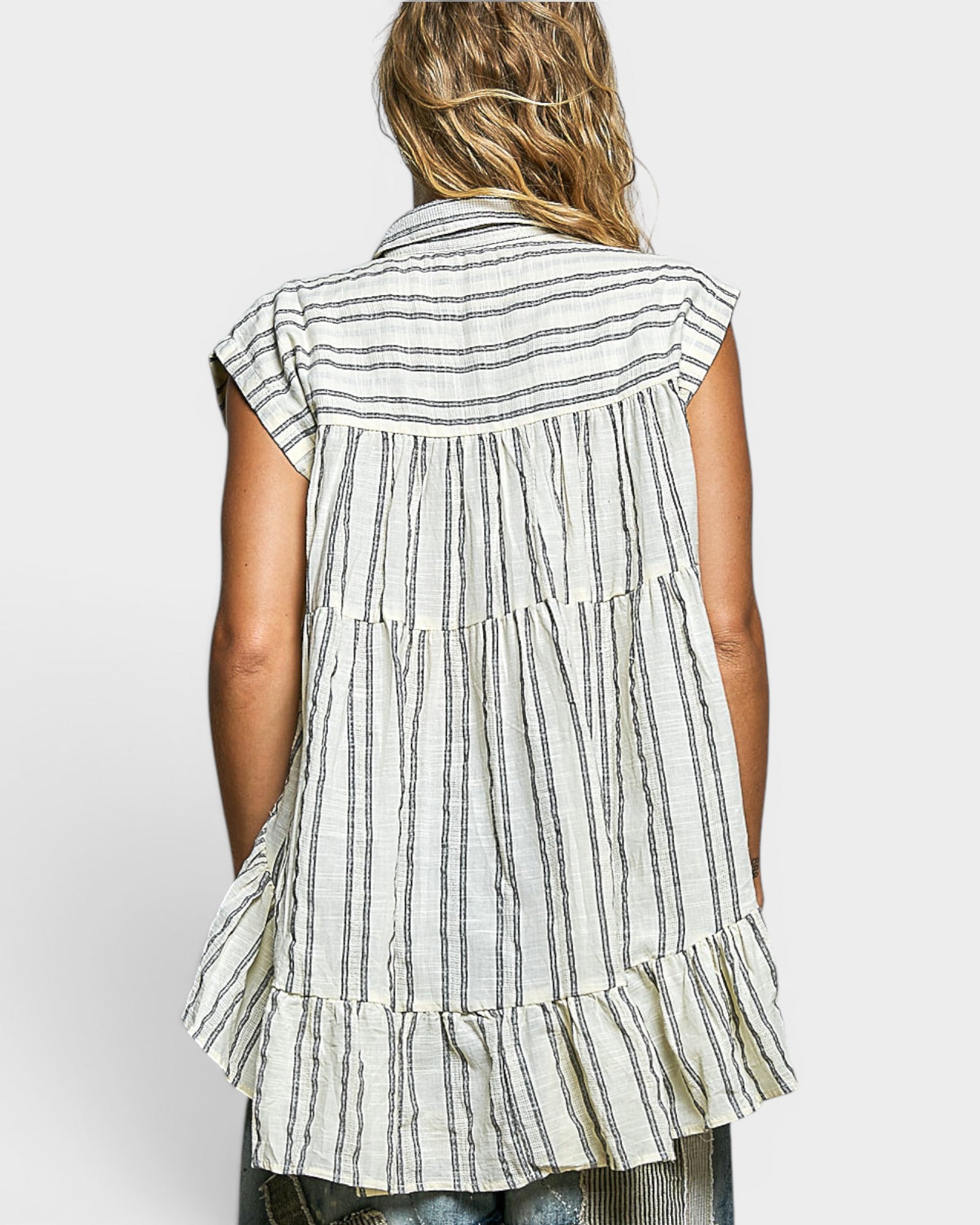 Woman wearing a sleeveless striped shirt with ruffled layers on a white background