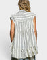 Woman wearing a sleeveless striped shirt with ruffled layers on a white background