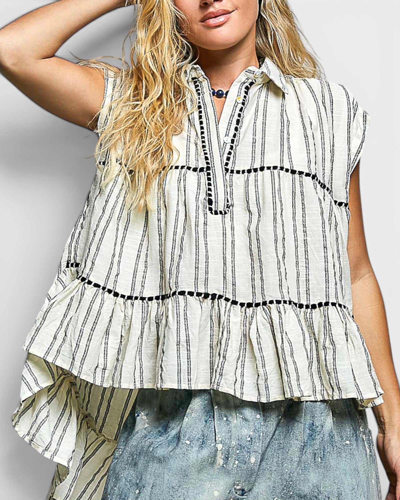 Woman wearing a sleeveless, striped blouse with a plain background