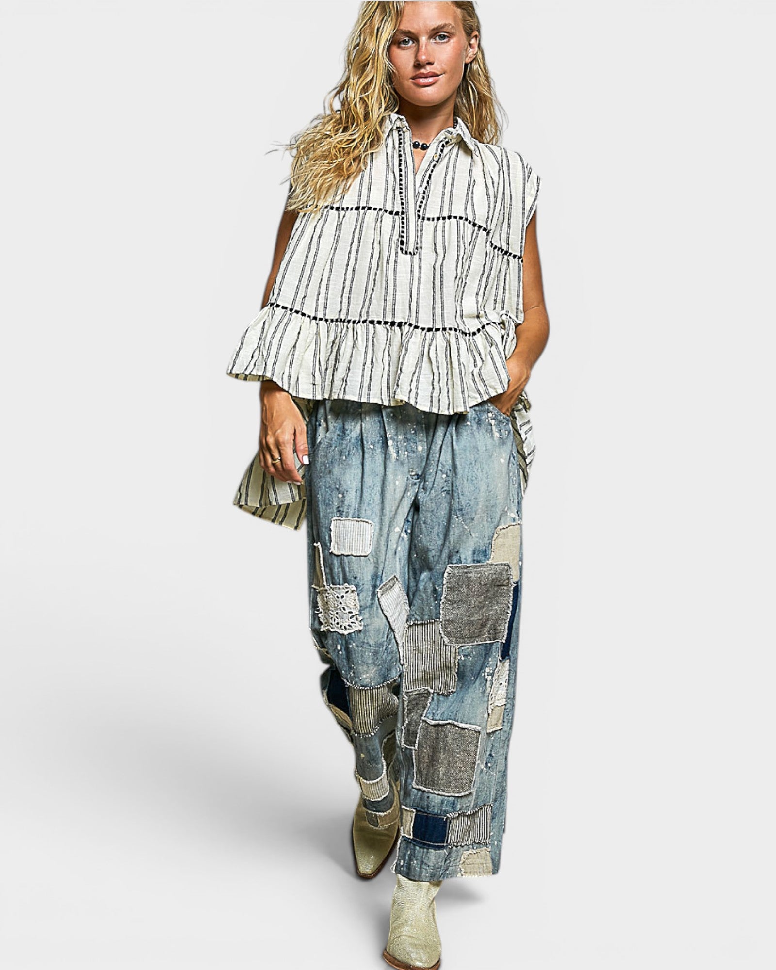 Woman wearing a striped top and patchwork jeans on a white background