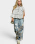 Woman wearing a striped top and patchwork jeans on a white background