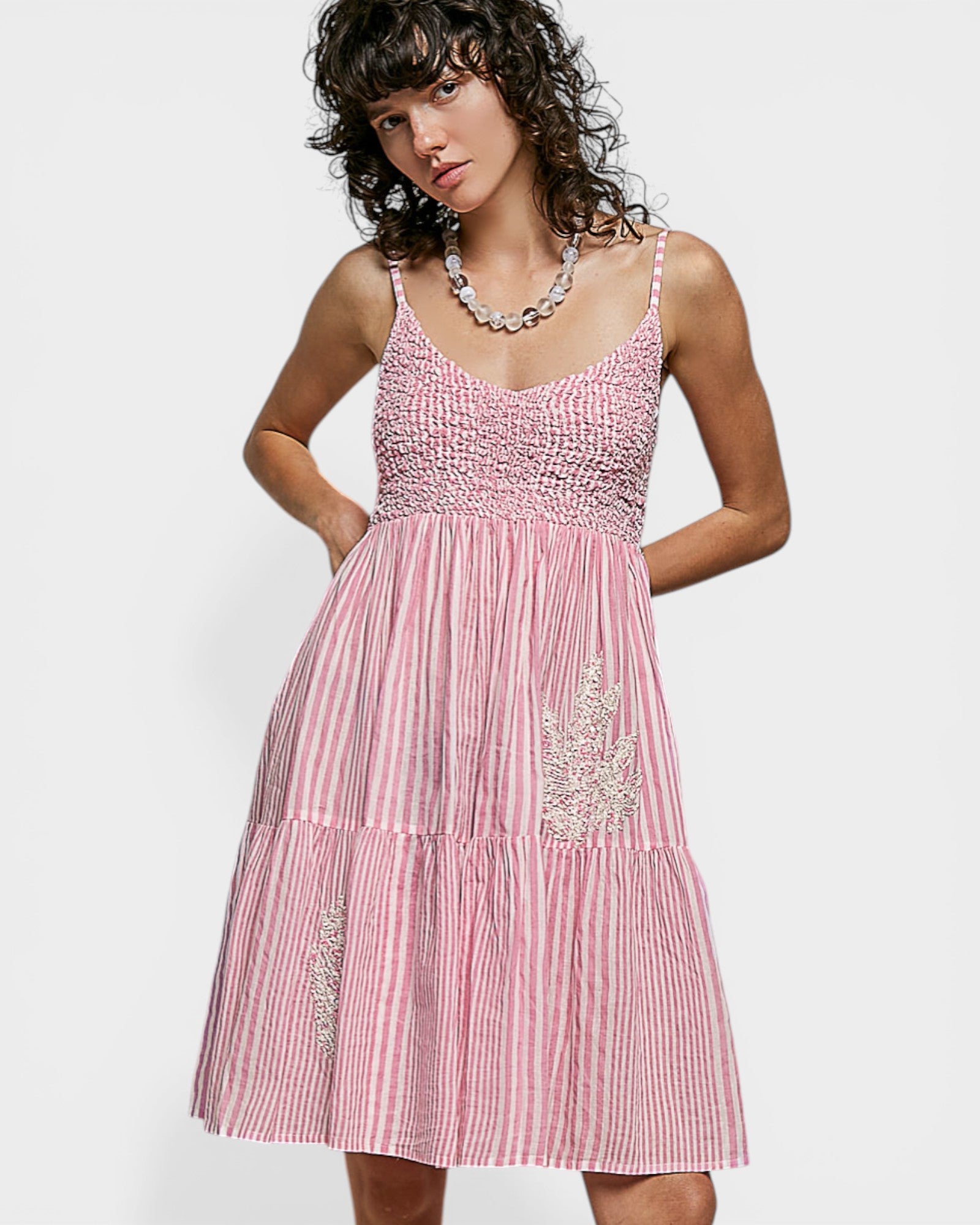 Woman wearing a pink dress with white stripes on a white background