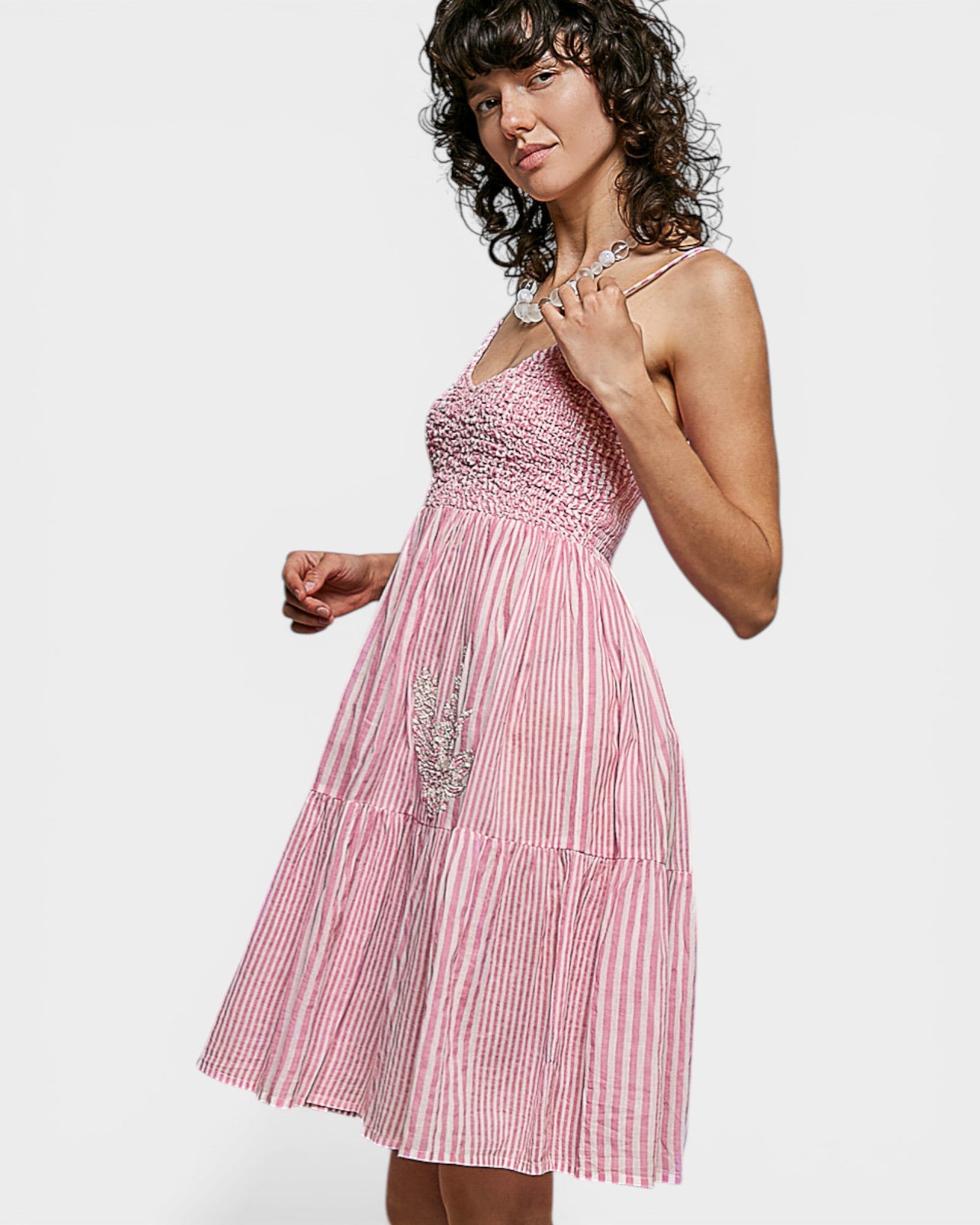 Woman wearing a pink and white striped dress with a plain background