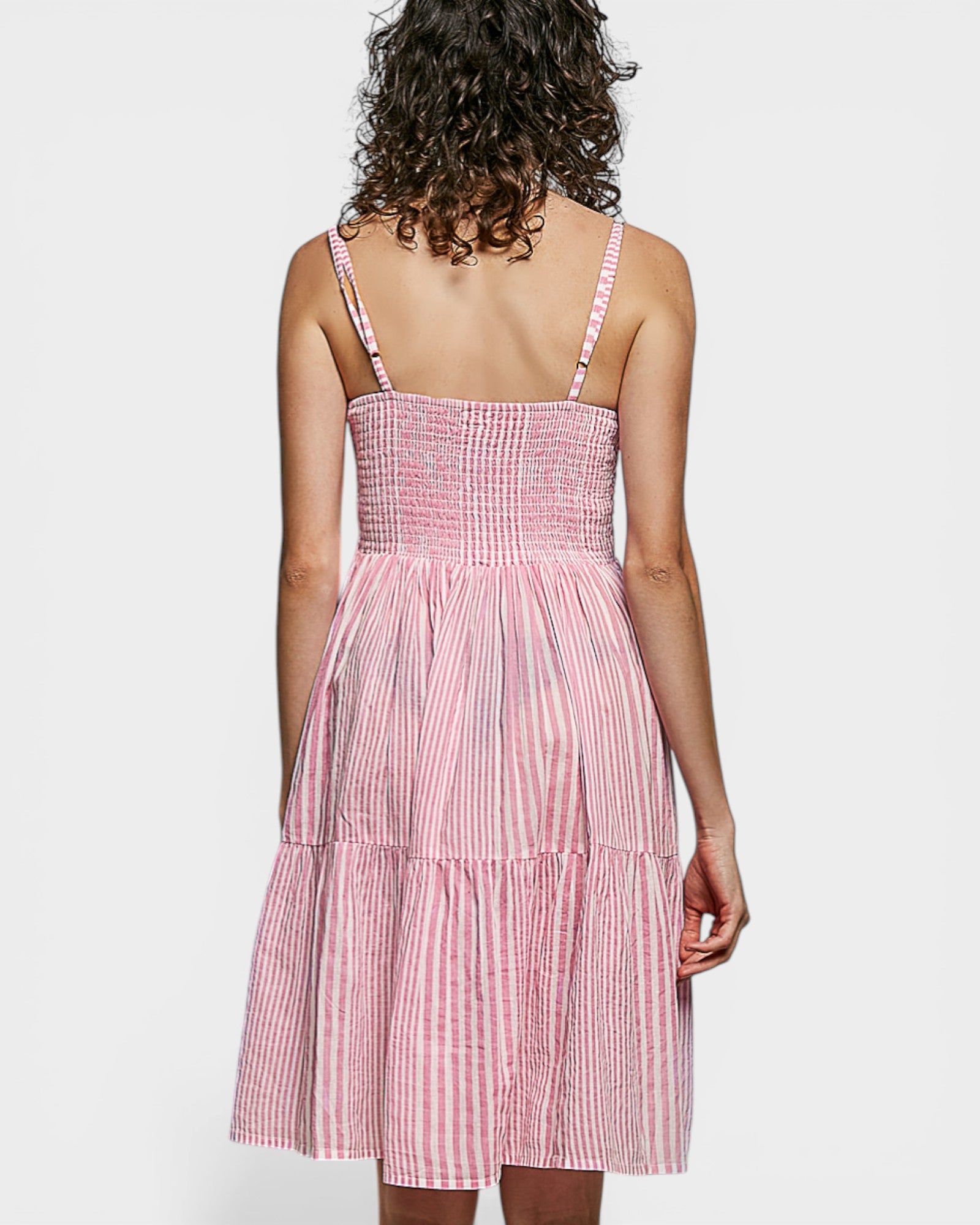 Woman wearing a pink and white checkered dress on a white background