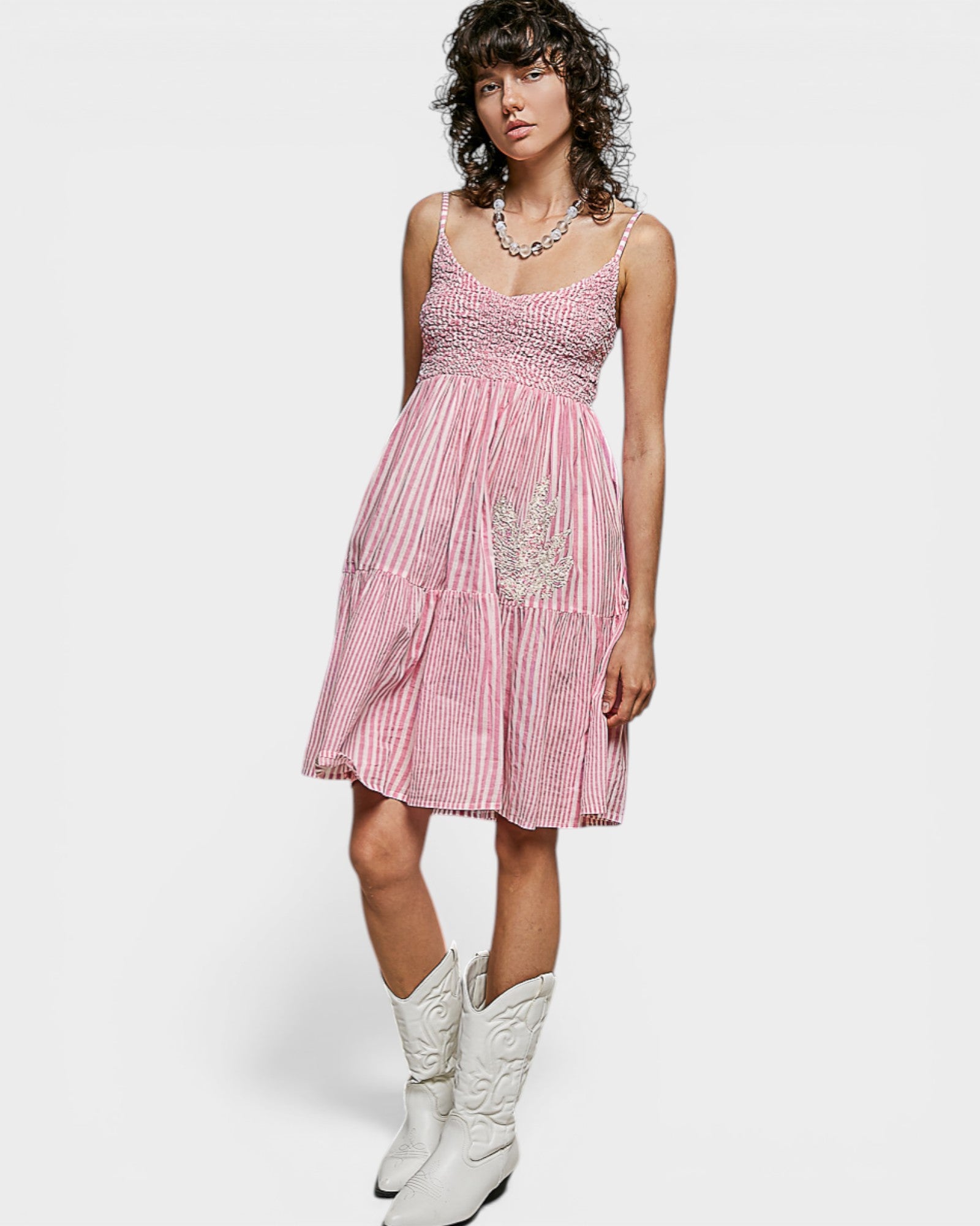Woman wearing a pink and white striped dress with a white background