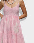 Pink dress with white stripes and embellishments on a plain background