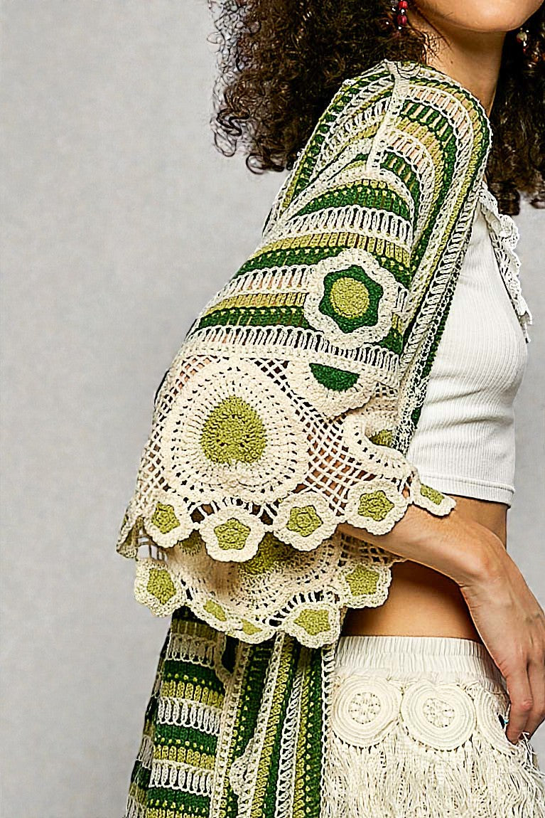 Person wearing a green and white crocheted shawl on a gray background