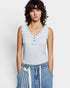 Woman wearing a light blue sleeveless top with button details against a plain background