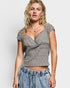 Woman wearing a gray lace top and blue denim pants on a white background