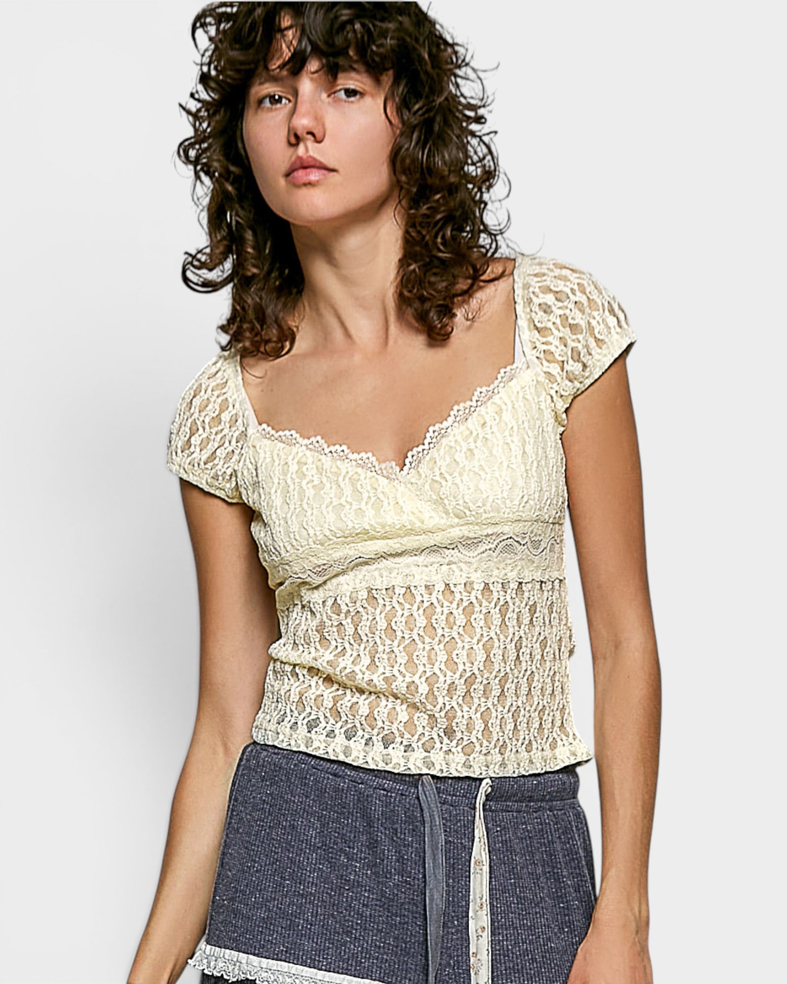 Woman wearing a lace top against a plain background