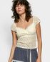 Woman wearing a lace top against a plain background