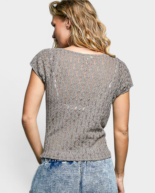 Woman wearing a patterned top and jeans on a plain background