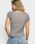 Woman wearing a patterned top and jeans on a plain background