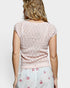 Woman wearing a light pink lace top and floral skirt on a white background