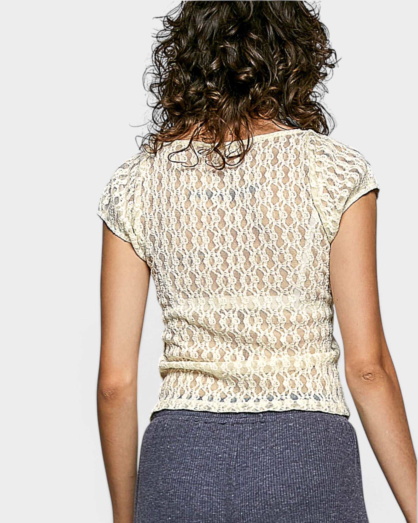 Person wearing a lace top with a plain background