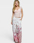 Woman wearing a pink lace top and floral pants on a white background