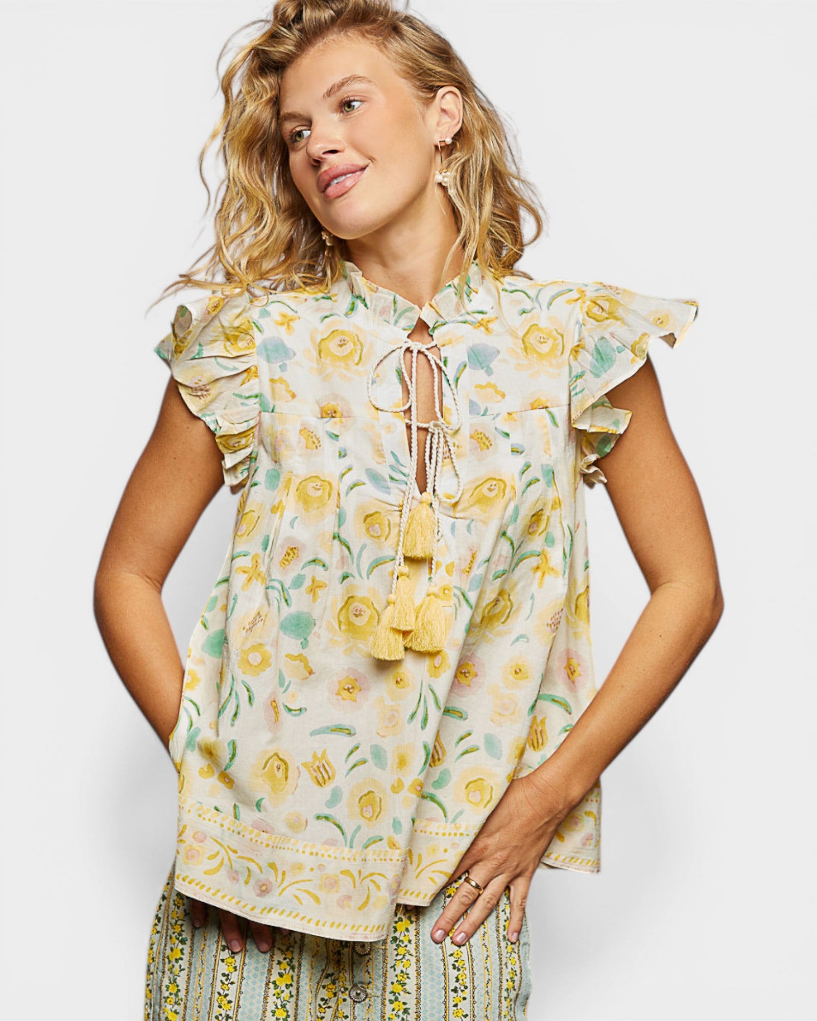 Woman wearing a floral blouse with ruffled sleeves on a white background