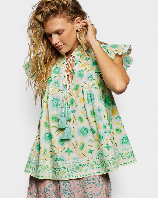 Woman wearing a floral dress with pom-pom details on a white background