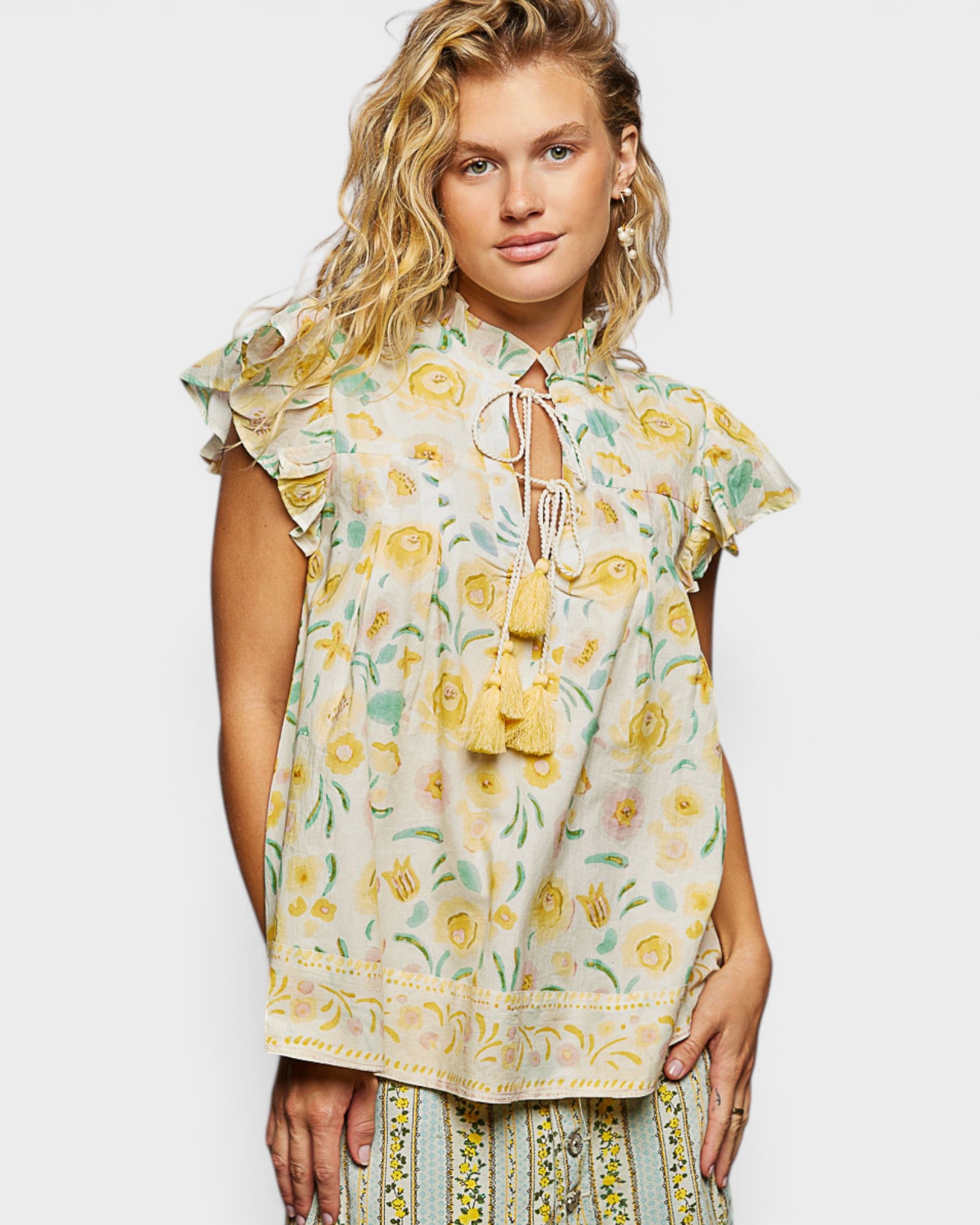 Woman wearing a floral dress with yellow and green pattern on a white background