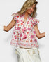 Woman wearing a floral blouse with ruffled sleeves on a white background