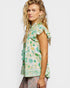 Woman wearing a green floral blouse with ruffled sleeves on a white background