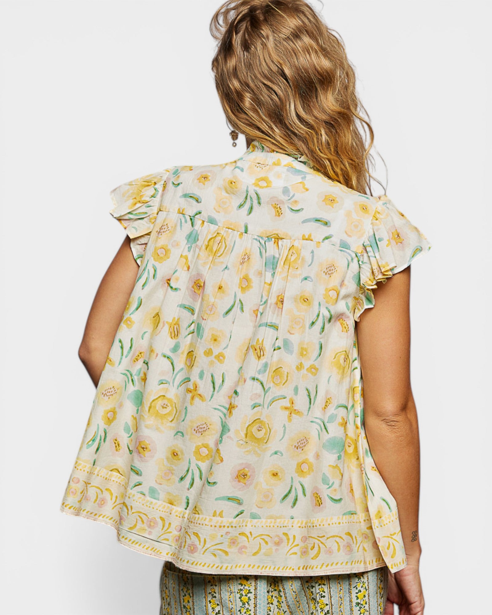 Woman wearing a floral blouse with ruffled sleeves on a white background