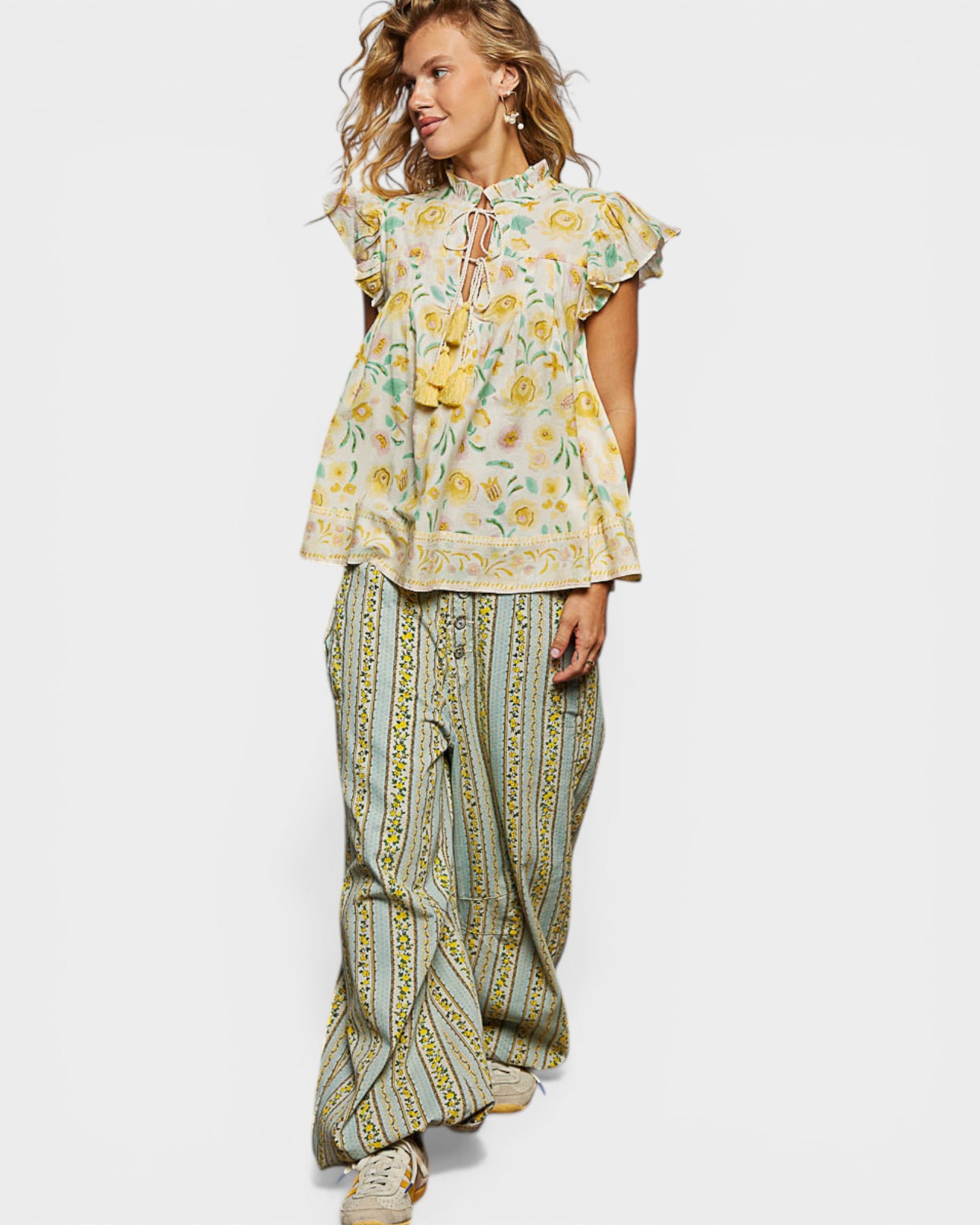 Woman wearing a floral top and patterned pants on a white background