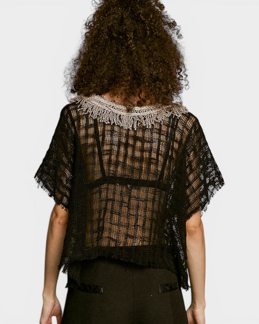 Person wearing a black checkered top with lace details on a white background
