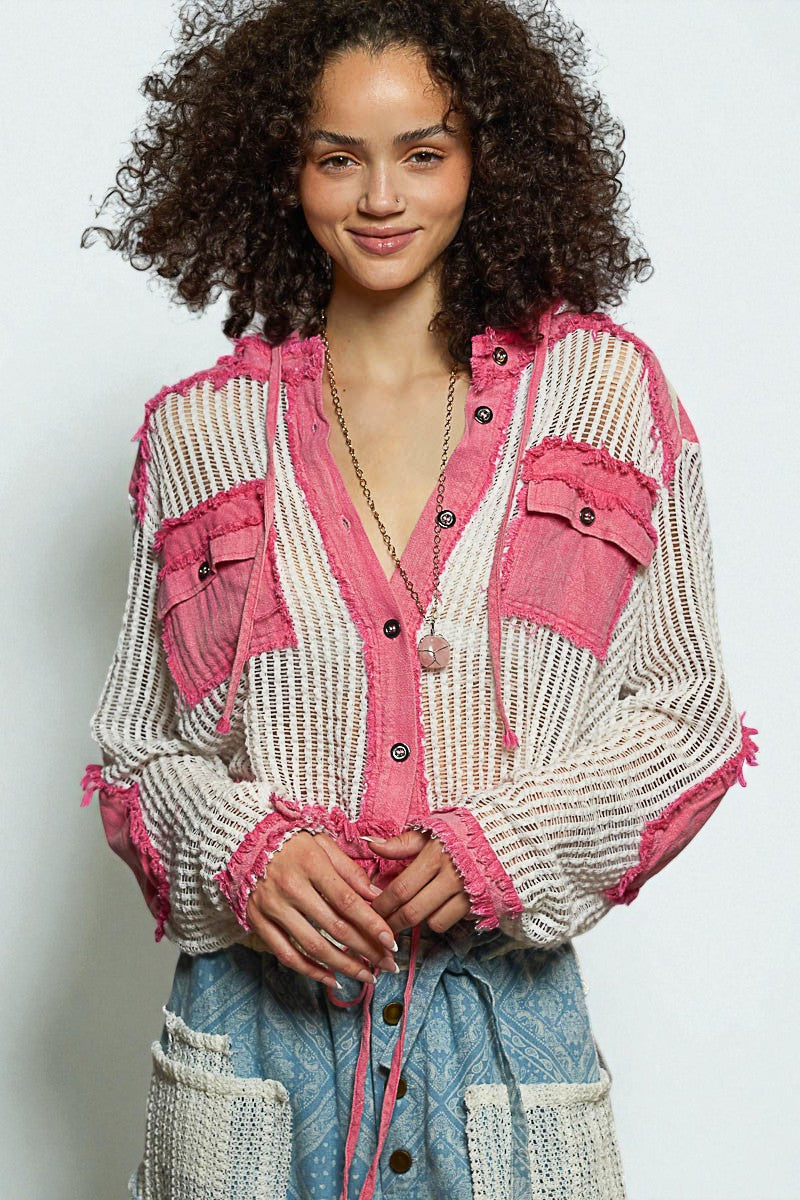 Woman wearing a pink and white patterned cardigan with a plain background