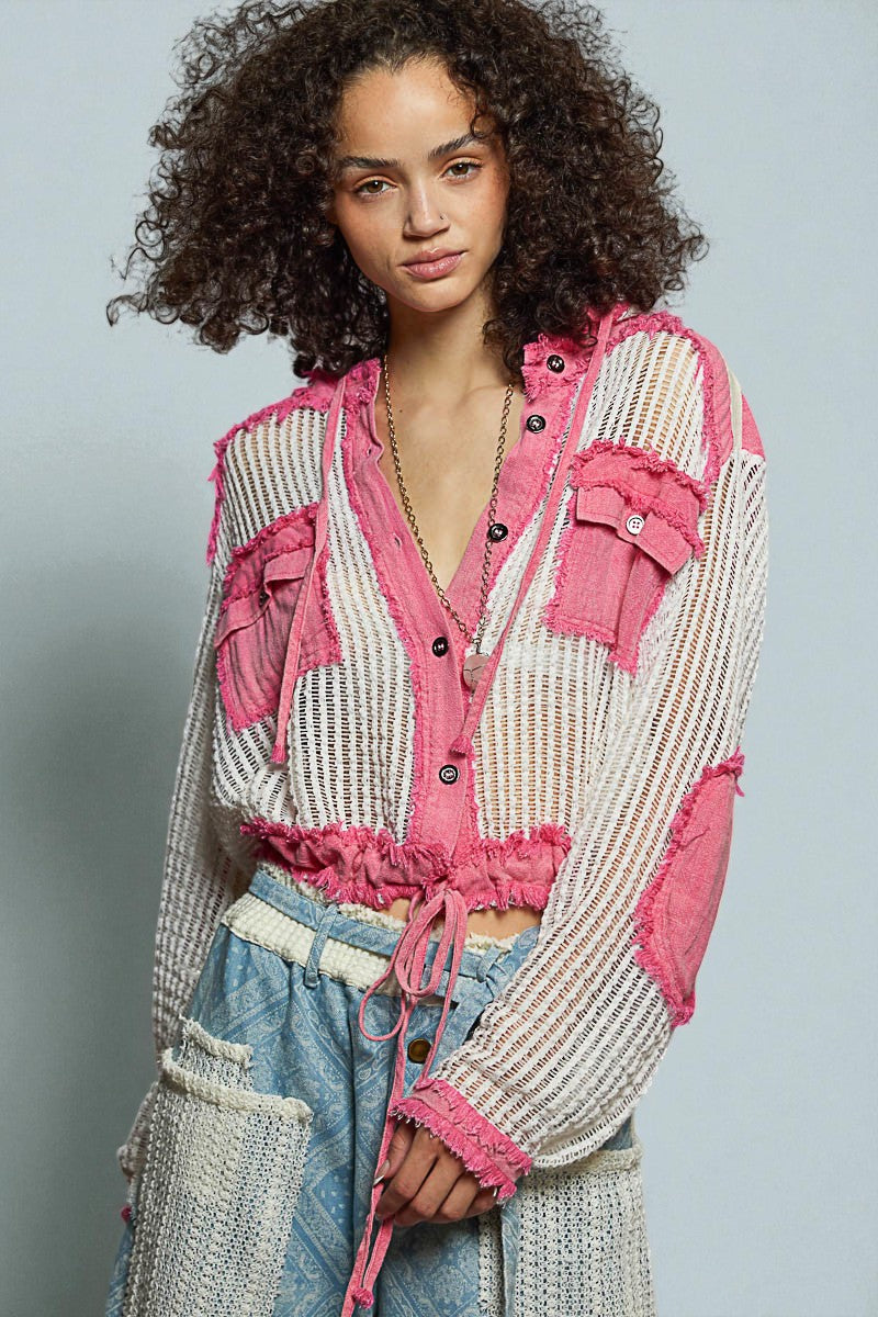 Woman wearing a colorful jacket with pink accents on a gray background