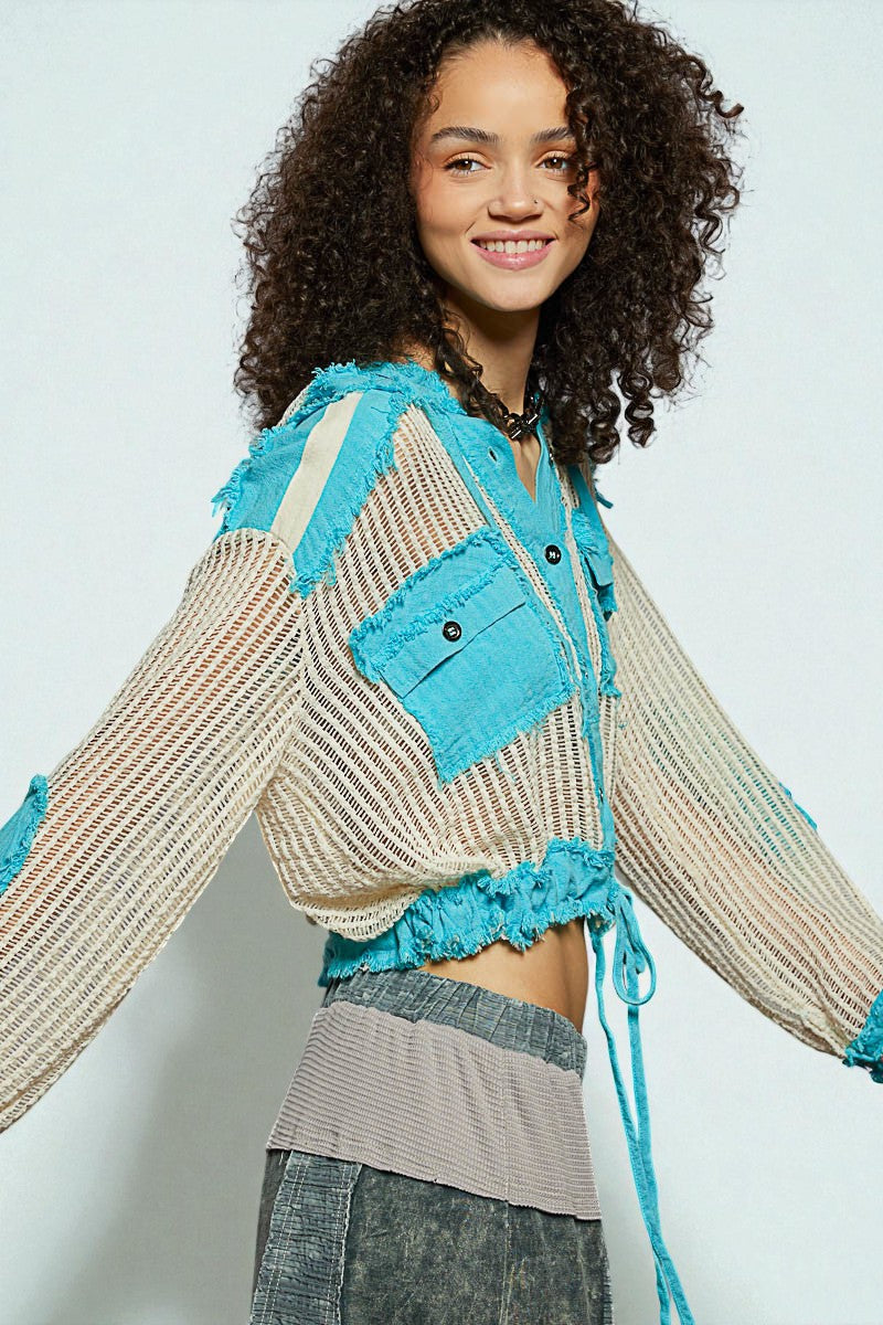 Woman wearing a colorful jacket with blue accents on a plain background