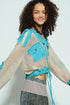 Woman wearing a colorful jacket with blue accents on a plain background