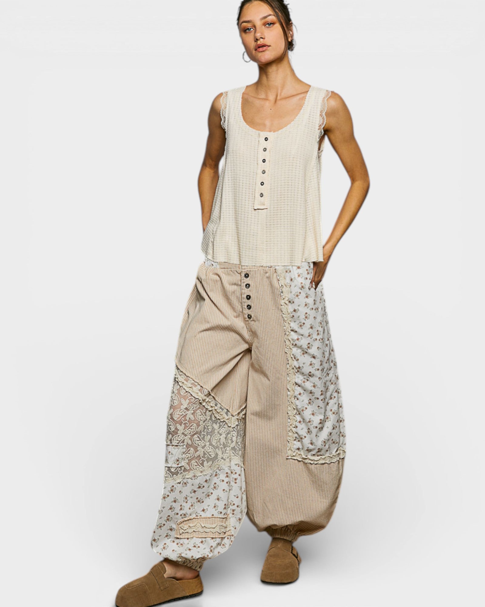 Woman wearing a sleeveless top and wide-leg pants with lace details on a white background