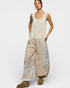 Woman wearing a sleeveless top and wide-leg pants with lace details on a white background