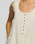 Close-up of a beige sleeveless top with buttons on a plain background