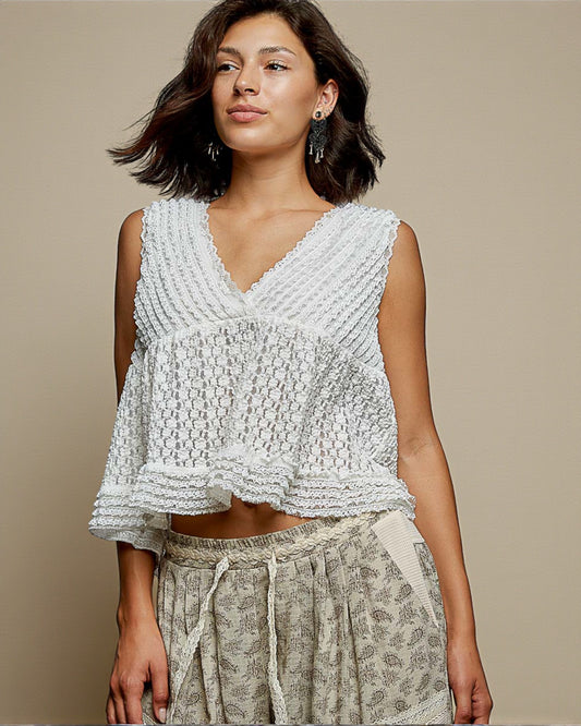 Woman wearing a textured white top and patterned pants against a beige background