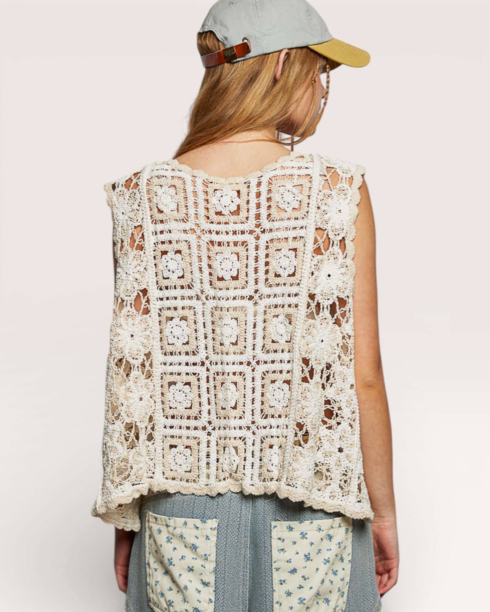 Person wearing a crochet vest with a plain background