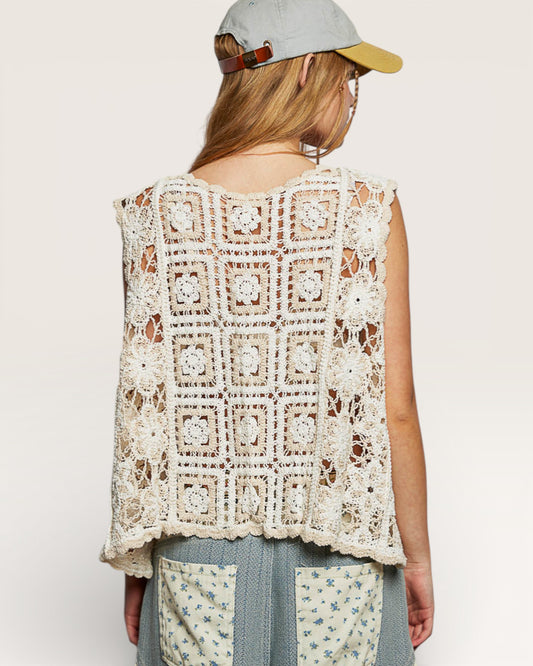 Person wearing a crochet vest with a plain background