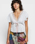 Woman wearing a white lace top with a colorful skirt on a plain background