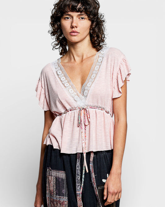 Woman wearing a pink blouse with lace details on a white background