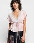 Woman wearing a pink blouse with lace details on a white background