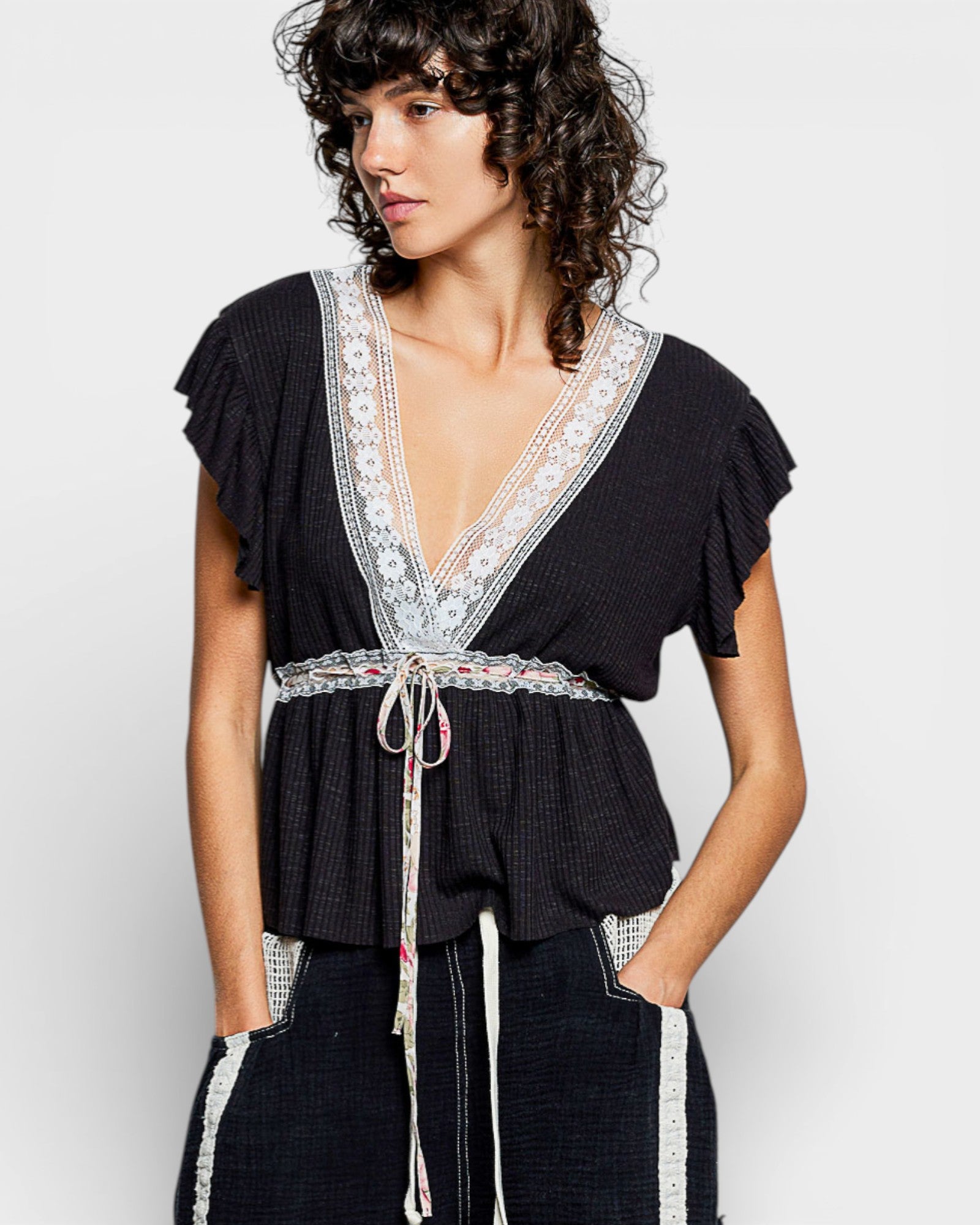 Woman wearing a black top with lace details on a white background