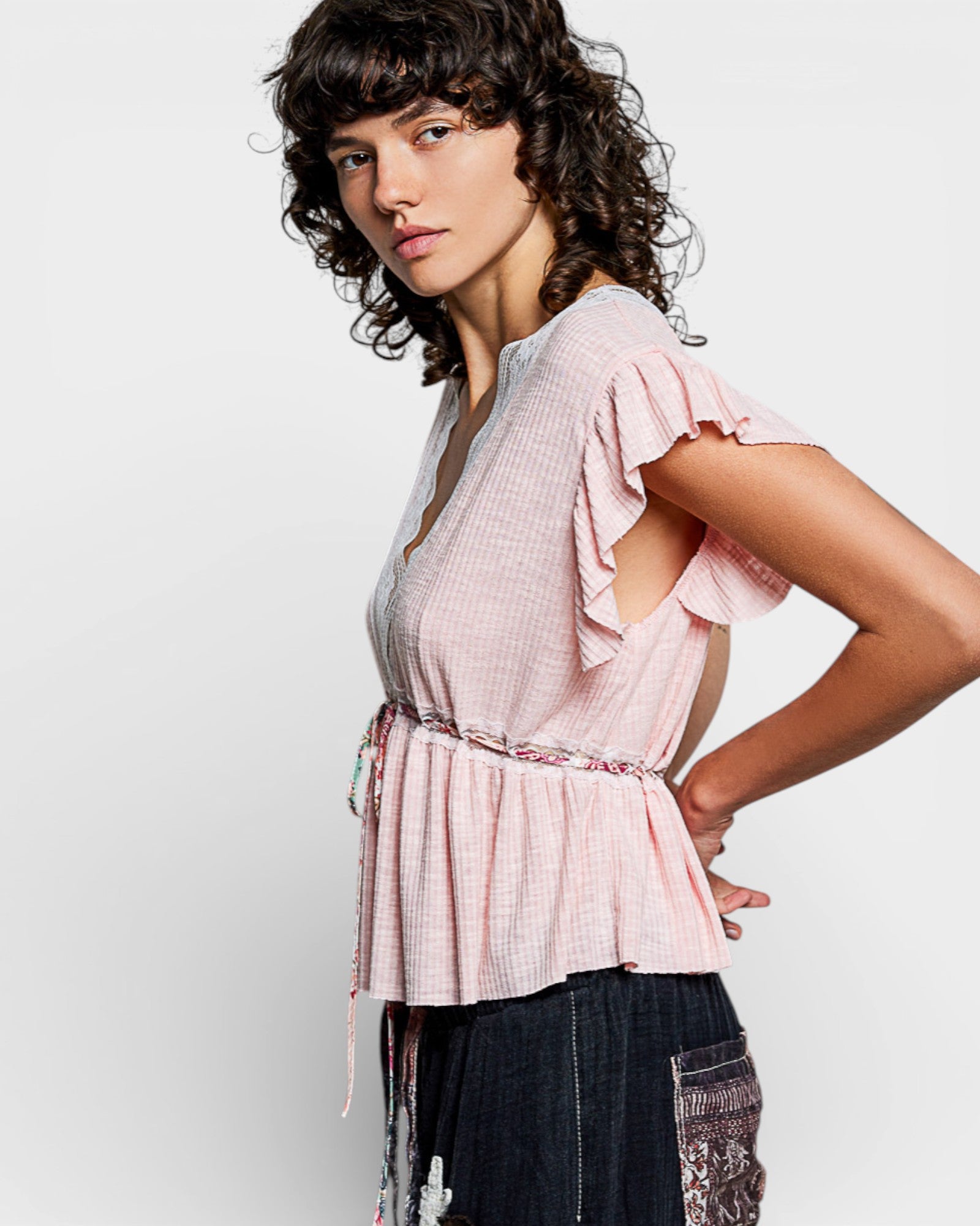 Woman wearing a light pink blouse with ruffled sleeves on a white background