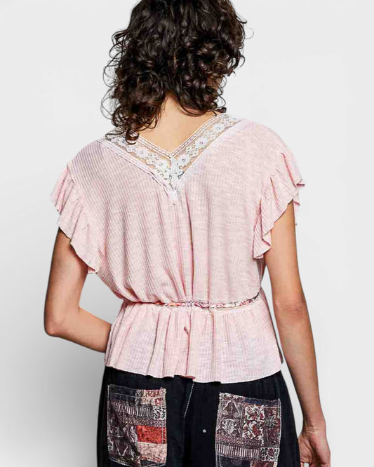 Woman wearing a pink blouse with lace details on a white background