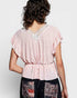 Woman wearing a pink blouse with lace details on a white background