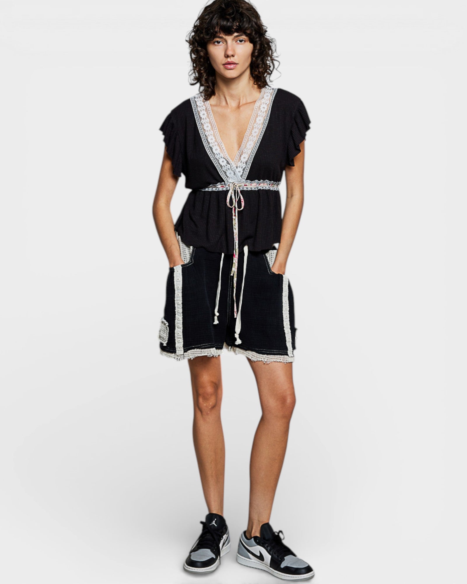 Woman wearing a black dress with white lace details on a white background