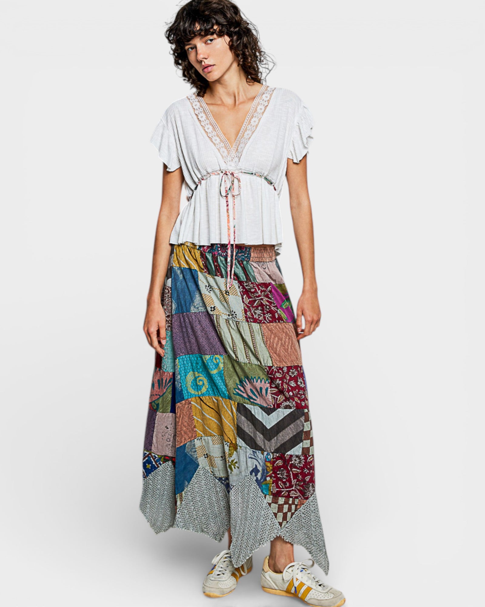 Woman wearing a white top and colorful patchwork skirt on a white background