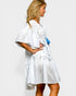 Woman wearing a white dress with a blue bag on a plain background