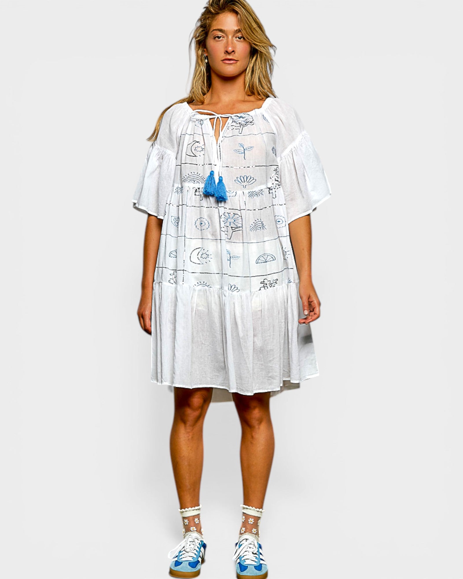 Woman wearing a white dress with blue accents on a plain background